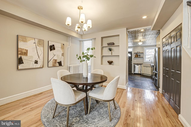 dining area featuring light wood finished floors, baseboards, a chandelier, and built in features