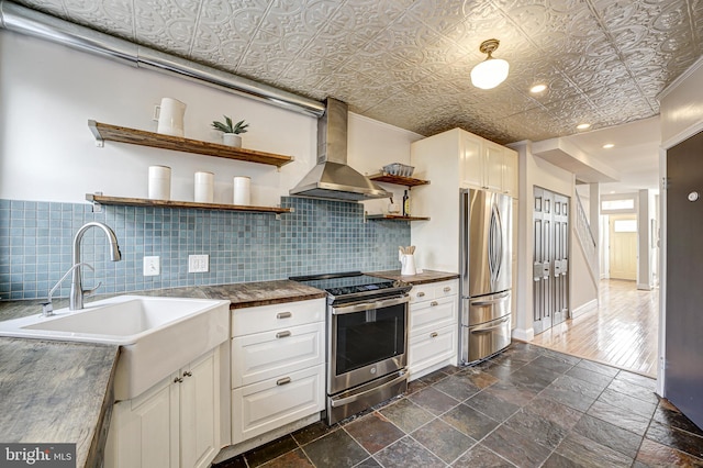 kitchen featuring wall chimney exhaust hood, an ornate ceiling, stainless steel appliances, open shelves, and a sink