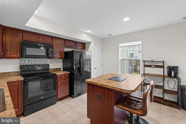 kitchen with a kitchen bar, black appliances, and a kitchen island