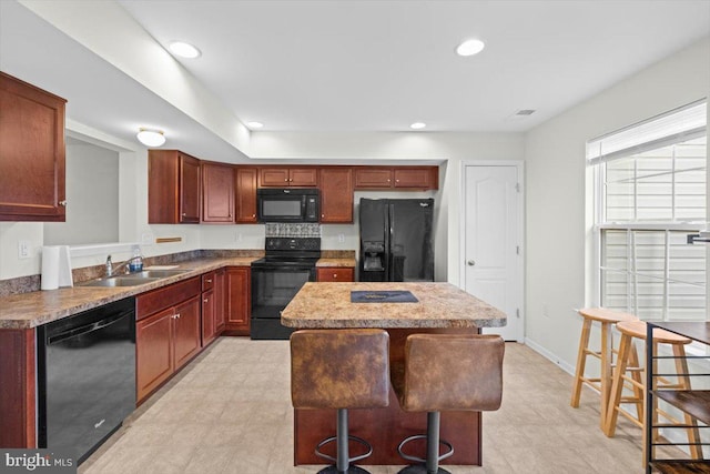 kitchen with a center island, sink, a kitchen breakfast bar, and black appliances