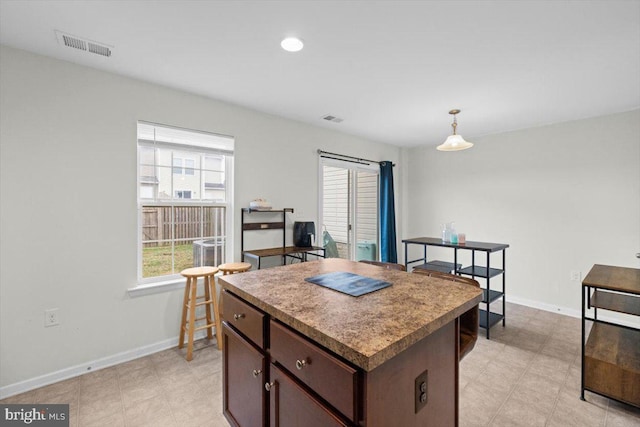 kitchen featuring pendant lighting, dark brown cabinets, and a center island