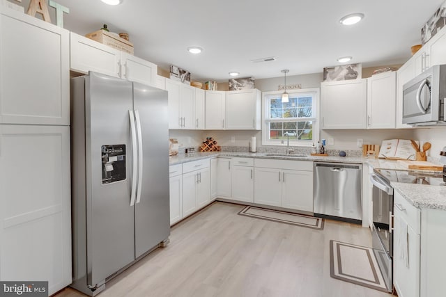 kitchen with pendant lighting, sink, appliances with stainless steel finishes, light stone countertops, and white cabinets