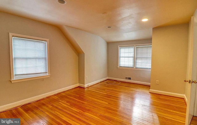 additional living space with vaulted ceiling and light wood-type flooring