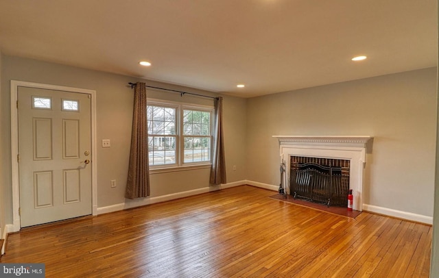 unfurnished living room featuring a brick fireplace and light wood-type flooring