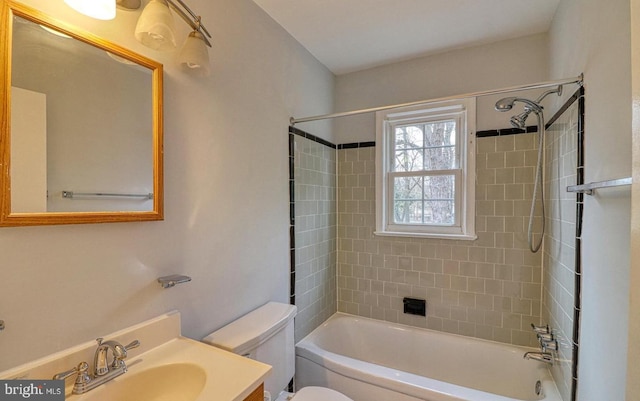 full bathroom featuring vanity, tiled shower / bath combo, and toilet