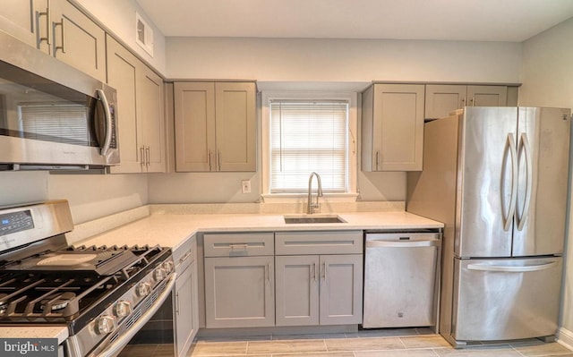 kitchen with appliances with stainless steel finishes, gray cabinets, and sink