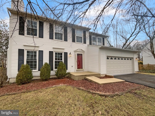 colonial inspired home with a garage, driveway, and a chimney