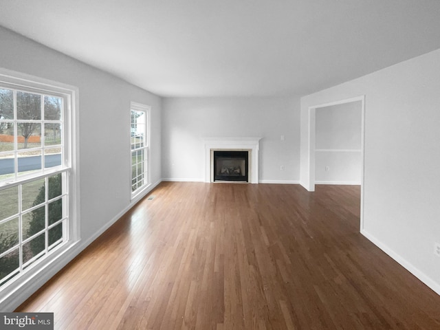 unfurnished living room with a fireplace, wood finished floors, and baseboards