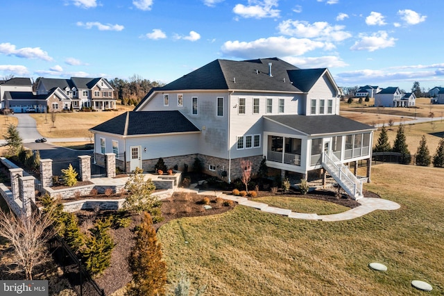 rear view of property featuring a sunroom and a lawn