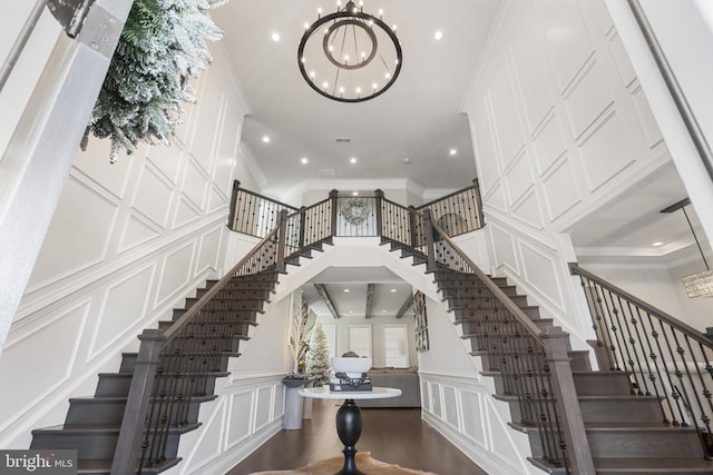 interior space with a high ceiling, crown molding, a chandelier, and hardwood / wood-style flooring