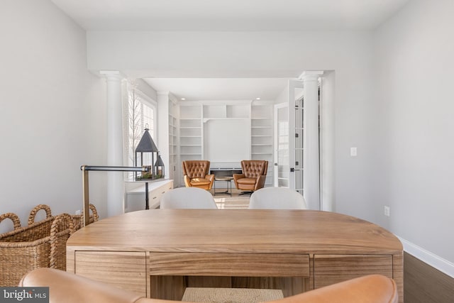 dining space with hardwood / wood-style flooring and ornate columns