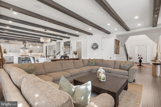 living room featuring hardwood / wood-style flooring, beam ceiling, and a notable chandelier