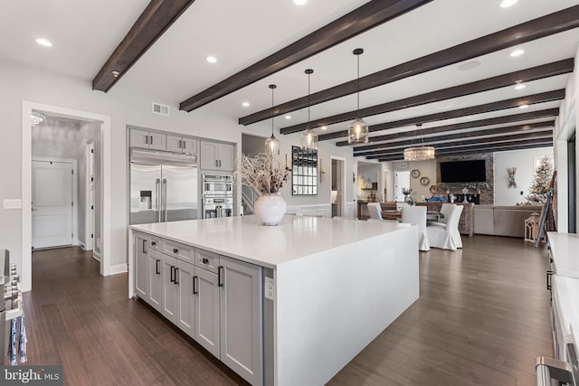 kitchen with dark wood-type flooring, gray cabinets, pendant lighting, stainless steel appliances, and a large island