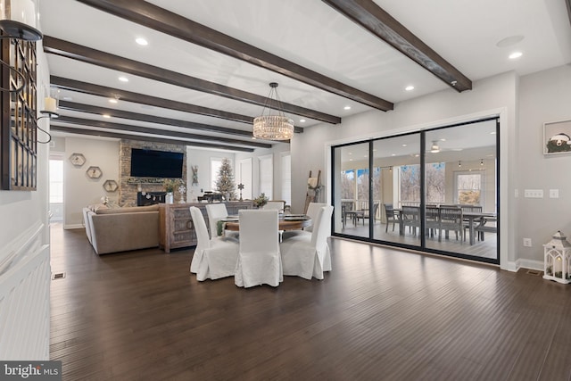 dining space with beam ceiling, dark wood-type flooring, and a fireplace