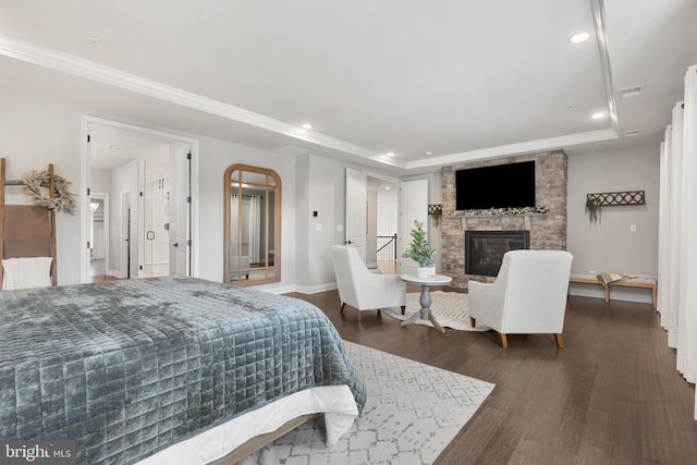 bedroom featuring crown molding, a fireplace, dark hardwood / wood-style flooring, and a raised ceiling