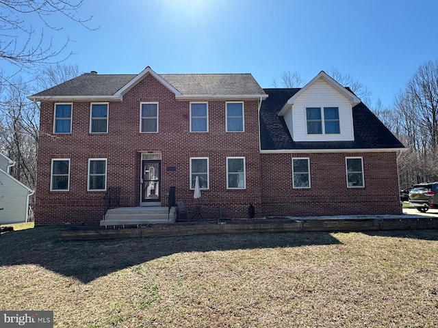 view of front of house with brick siding, a front lawn, and roof with shingles