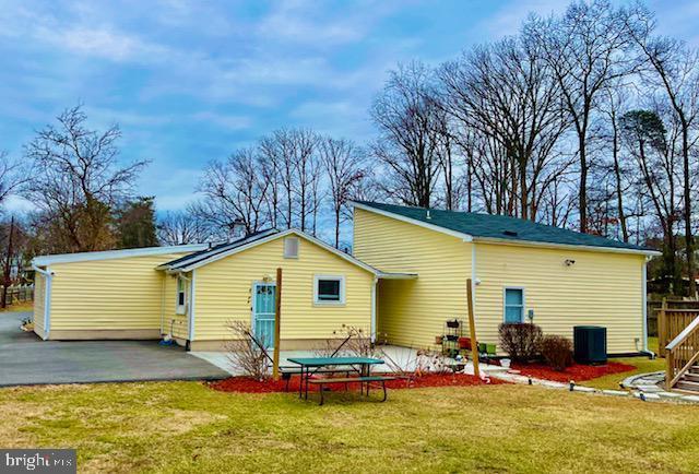 rear view of property featuring a patio, a yard, and central air condition unit