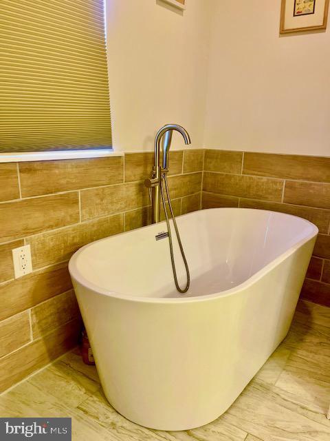 bathroom with tile walls and a tub to relax in