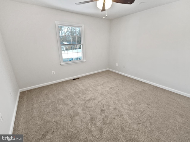 carpeted empty room featuring visible vents, baseboards, and a ceiling fan