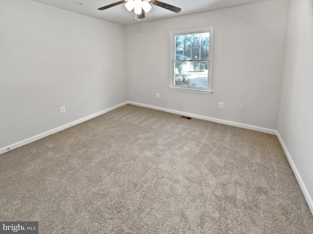 empty room with carpet floors, visible vents, baseboards, and a ceiling fan