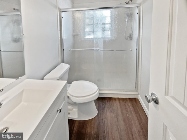 bathroom featuring vanity, a stall shower, wood finished floors, and toilet