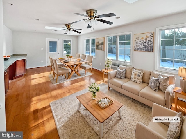 living room with ceiling fan, light wood finished floors, and baseboards