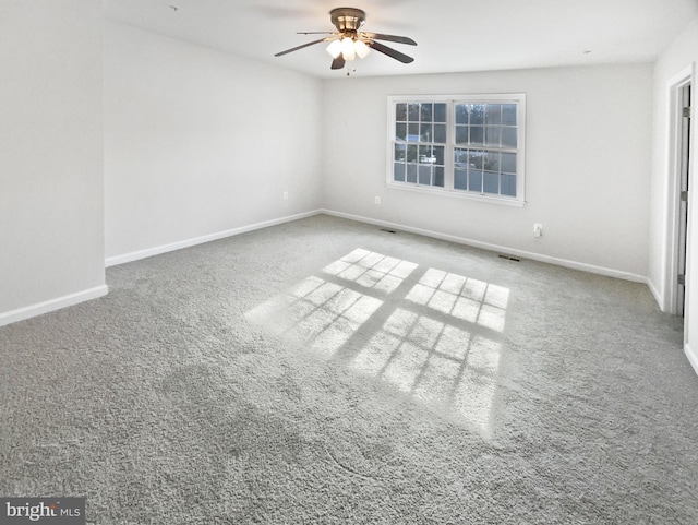 carpeted spare room featuring baseboards and a ceiling fan