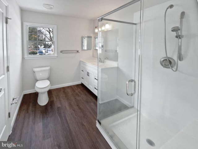 full bathroom with baseboards, toilet, wood finished floors, vanity, and a shower stall