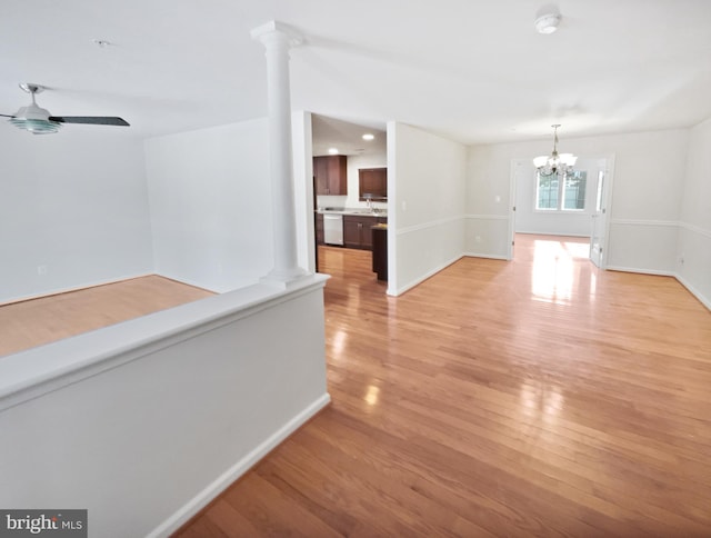 interior space with decorative columns, baseboards, light wood-type flooring, a sink, and ceiling fan with notable chandelier