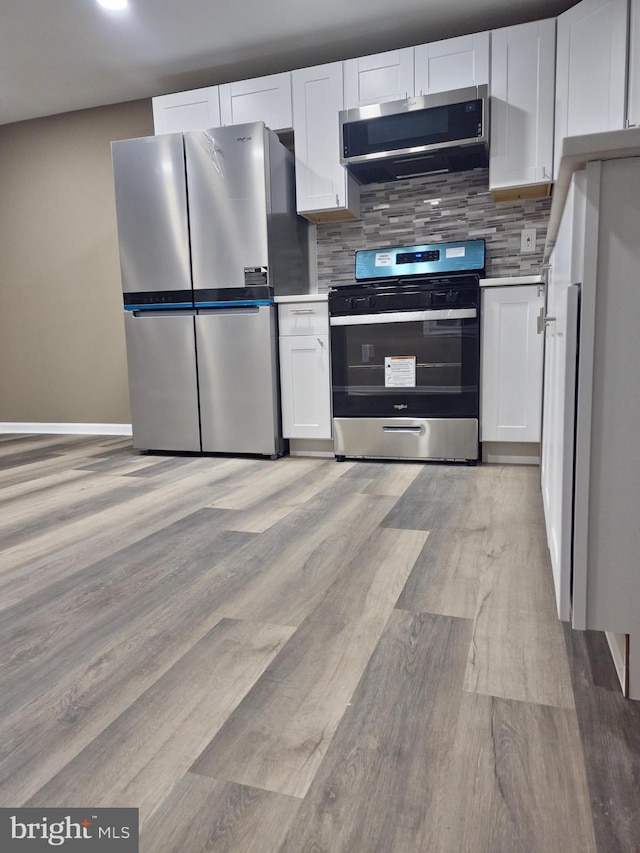 kitchen with backsplash, white cabinets, and appliances with stainless steel finishes