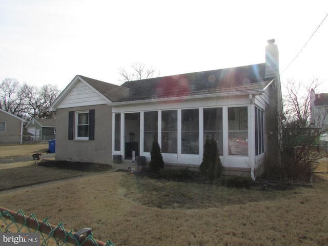 rear view of property featuring a sunroom and a lawn