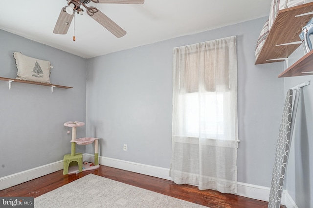 recreation room with dark wood-style floors, ceiling fan, and baseboards