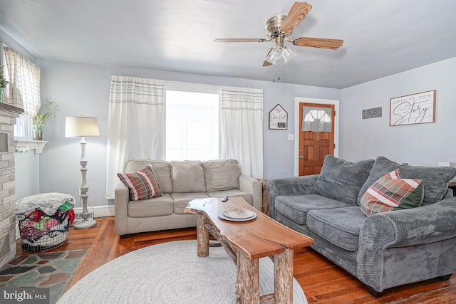 living room with dark wood-type flooring, a wealth of natural light, a brick fireplace, and ceiling fan