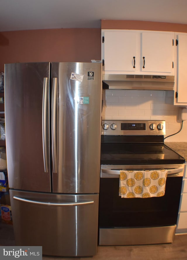 kitchen featuring appliances with stainless steel finishes, white cabinets, under cabinet range hood, and tasteful backsplash