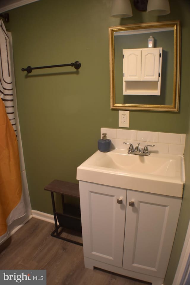 full bath with wood finished floors, vanity, and baseboards