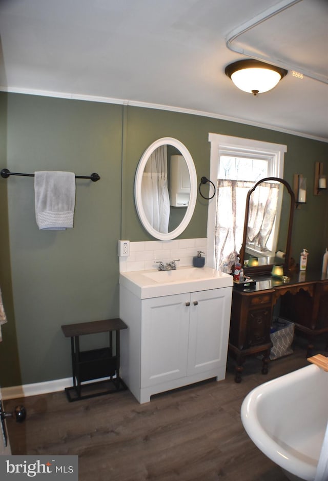 bathroom featuring ornamental molding, backsplash, vanity, and wood finished floors