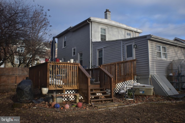 back of house with a deck, a chimney, and fence