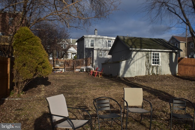 view of yard with fence, a deck, and an outdoor structure