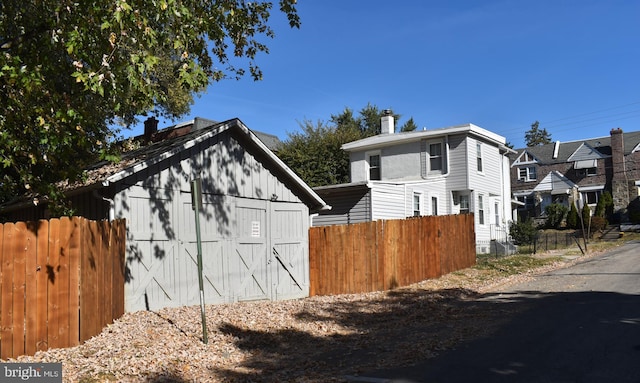 view of front of house with a chimney, fence, and an outbuilding