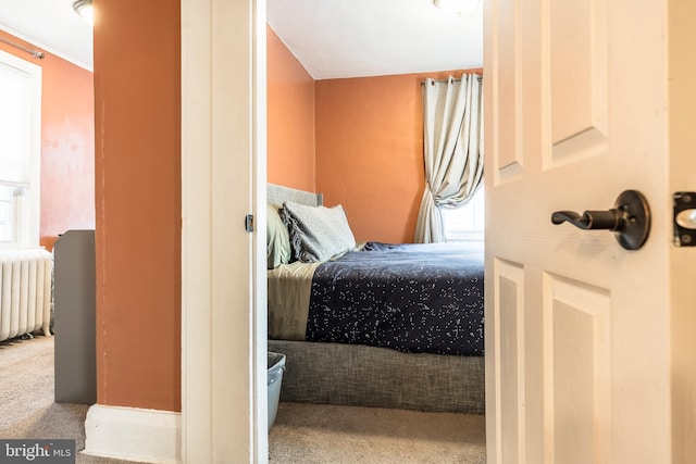 bedroom featuring multiple windows, radiator heating unit, and carpet flooring