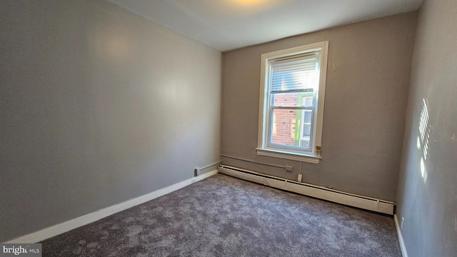 carpeted spare room with a baseboard heating unit