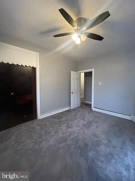 unfurnished bedroom featuring ceiling fan and dark carpet