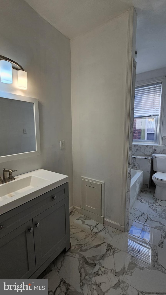 bathroom with vanity, a bath, and toilet