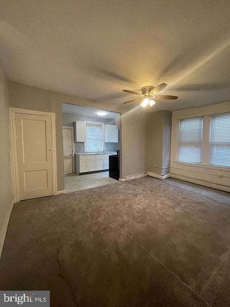 unfurnished living room with ceiling fan and carpet