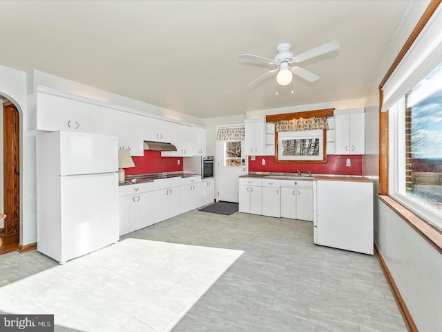 kitchen featuring decorative backsplash, oven, white refrigerator, and white cabinets