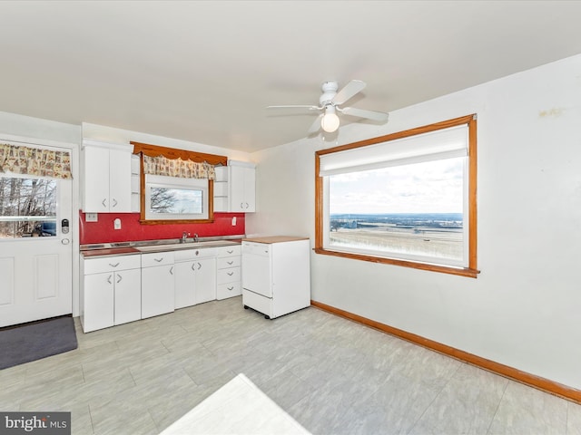 kitchen featuring sink, ceiling fan, white dishwasher, white cabinets, and decorative backsplash