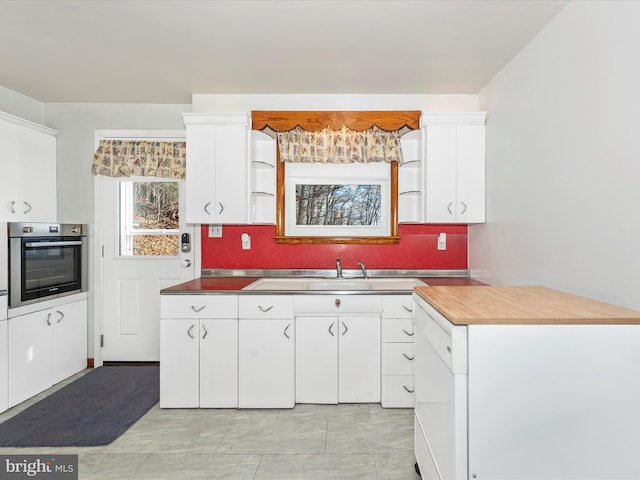 kitchen with sink, backsplash, dishwasher, stainless steel oven, and white cabinets