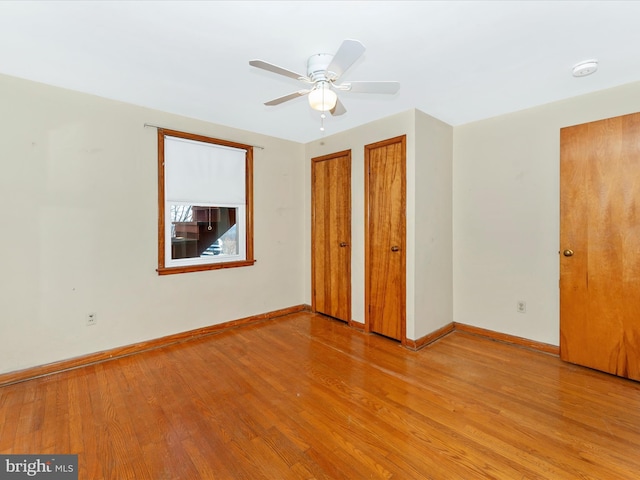 unfurnished bedroom featuring ceiling fan, two closets, and light wood-type flooring