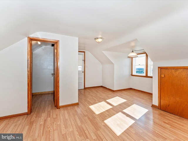 additional living space featuring light wood-type flooring and vaulted ceiling