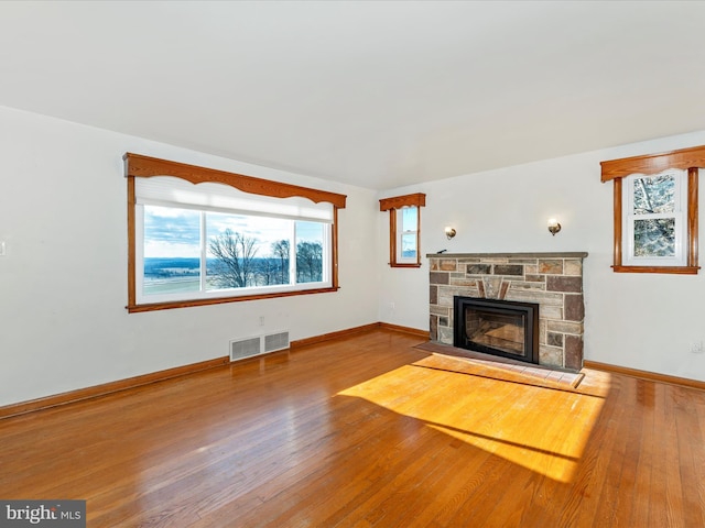 unfurnished living room with a stone fireplace and hardwood / wood-style floors